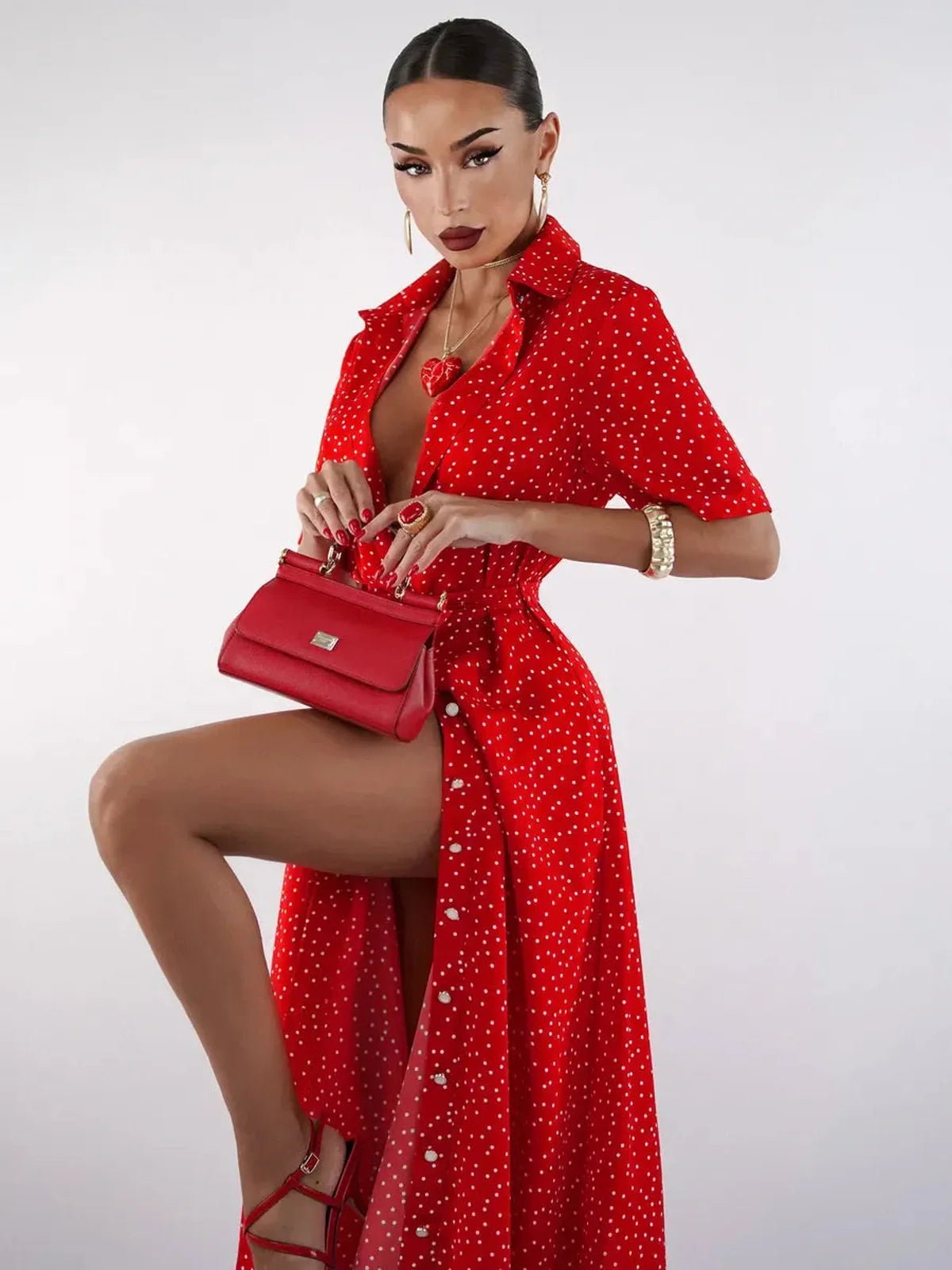 Model showcasing a vibrant red midi dress with polka dots, accessorized with a matching handbag, exuding playful elegance.