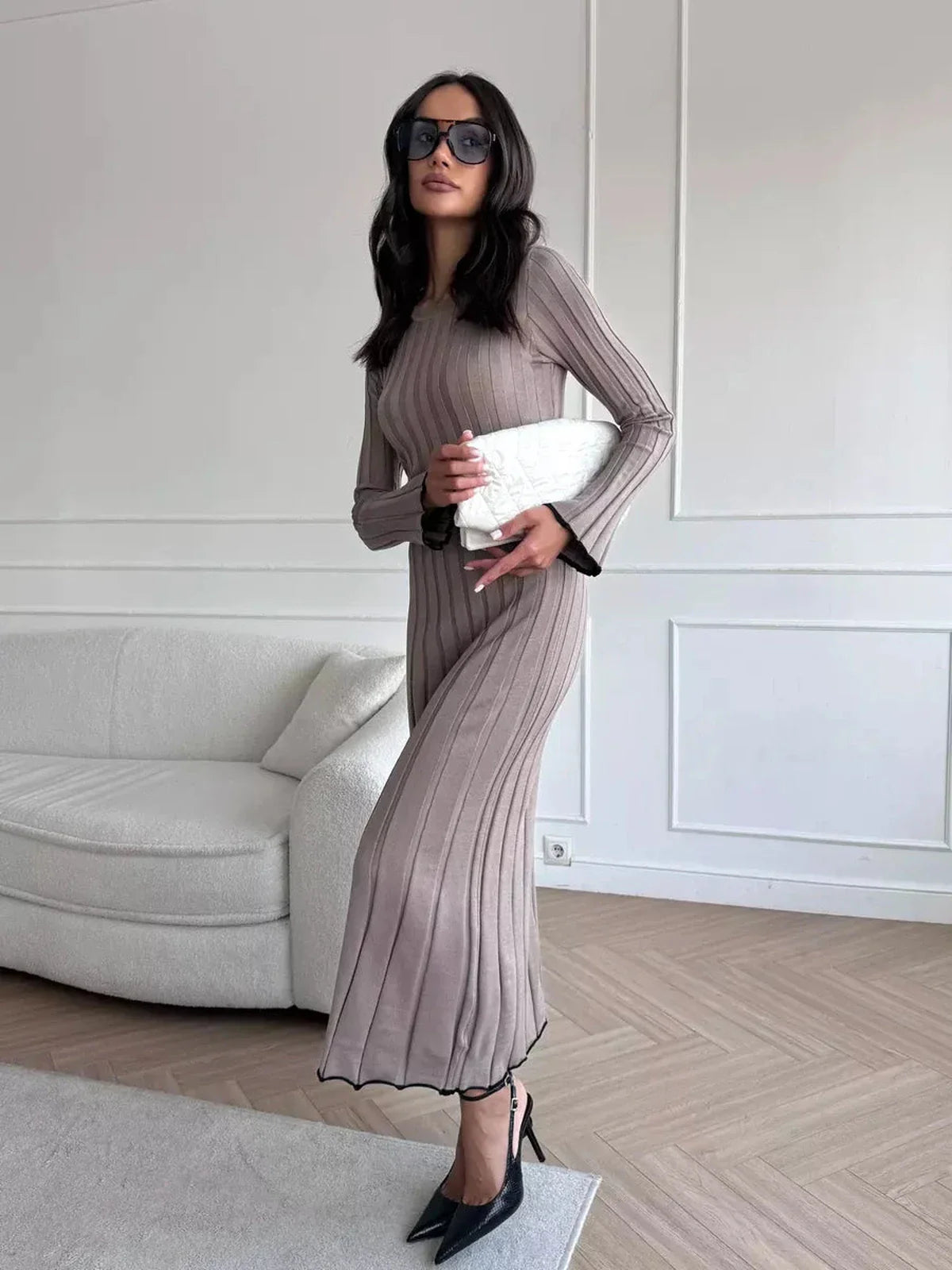 Model showcasing a Contour Maxi Dress in ribbed knit, styled with sunglasses and a clutch in a chic indoor setting.