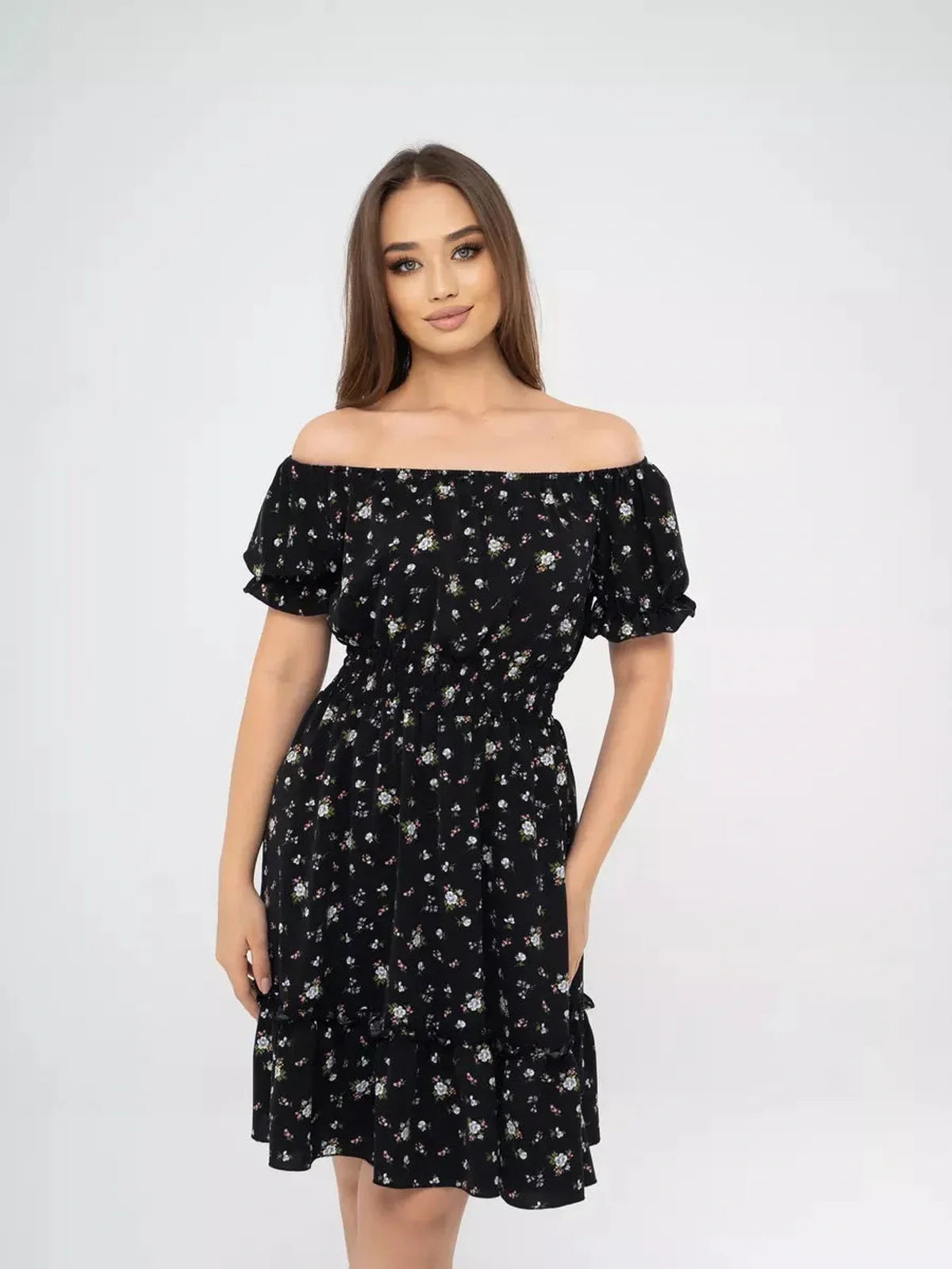 Model showcasing the Midnight Bloom black dress with floral print, off-shoulder neckline, and tiered skirt.