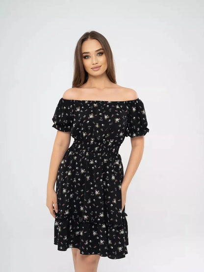 Model showcasing the Midnight Bloom black dress with floral print, off-shoulder neckline, and tiered skirt.