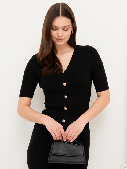 Model showcasing the Sculpted Grace Midi Dress, a fitted black rib knit dress with gold button details.