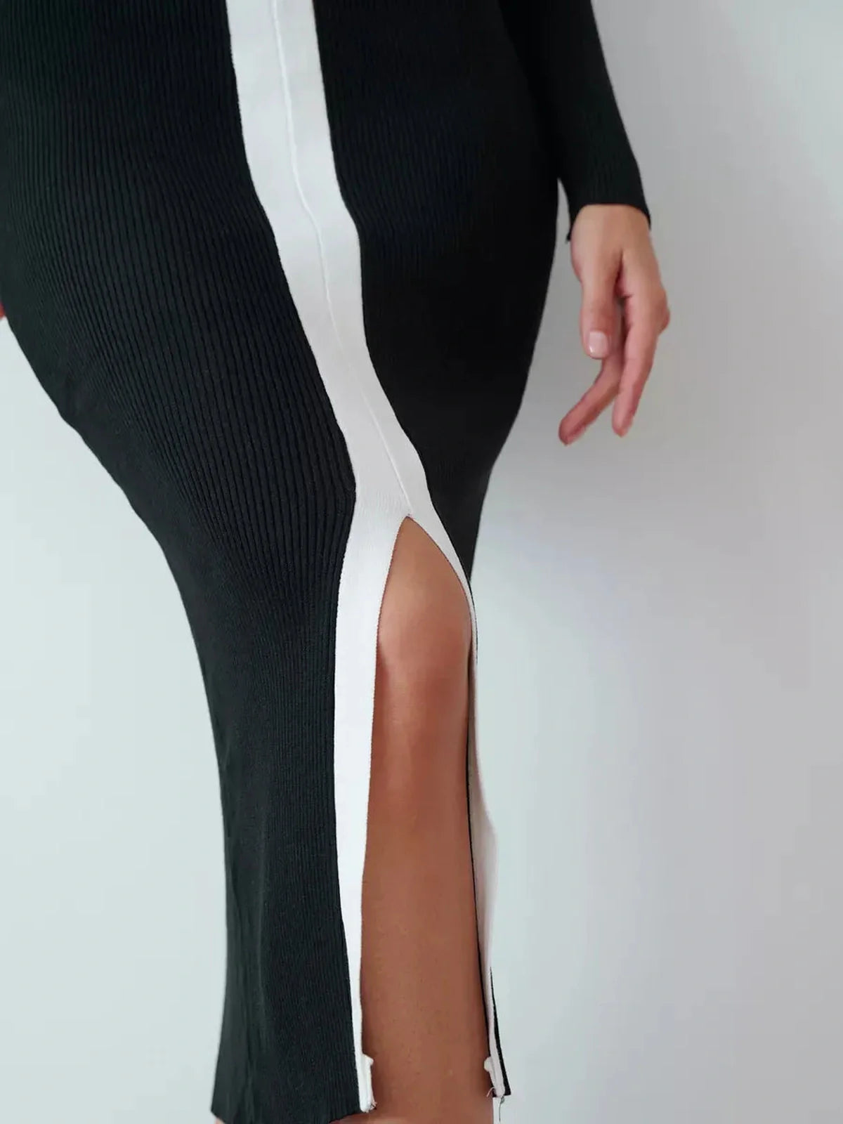 Close-up of the Contour Line Midi Dress showcasing its black fabric, contrast piping, and dramatic center slit.