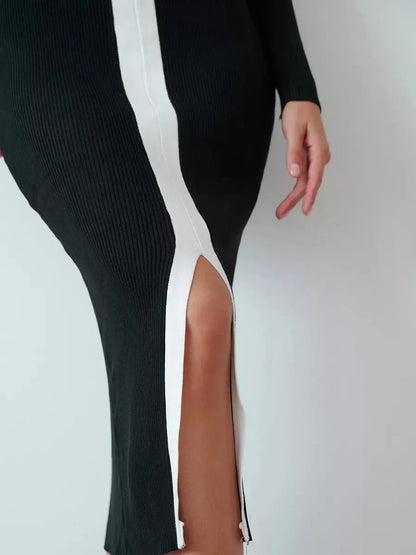 Close-up of the Contour Line Midi Dress showcasing its black fabric, contrast piping, and dramatic center slit.
