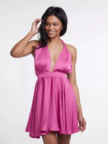 A model showcases the Pink Mirage mini dress, featuring a plunging V-neck and flared skirt in vibrant floral pink.
