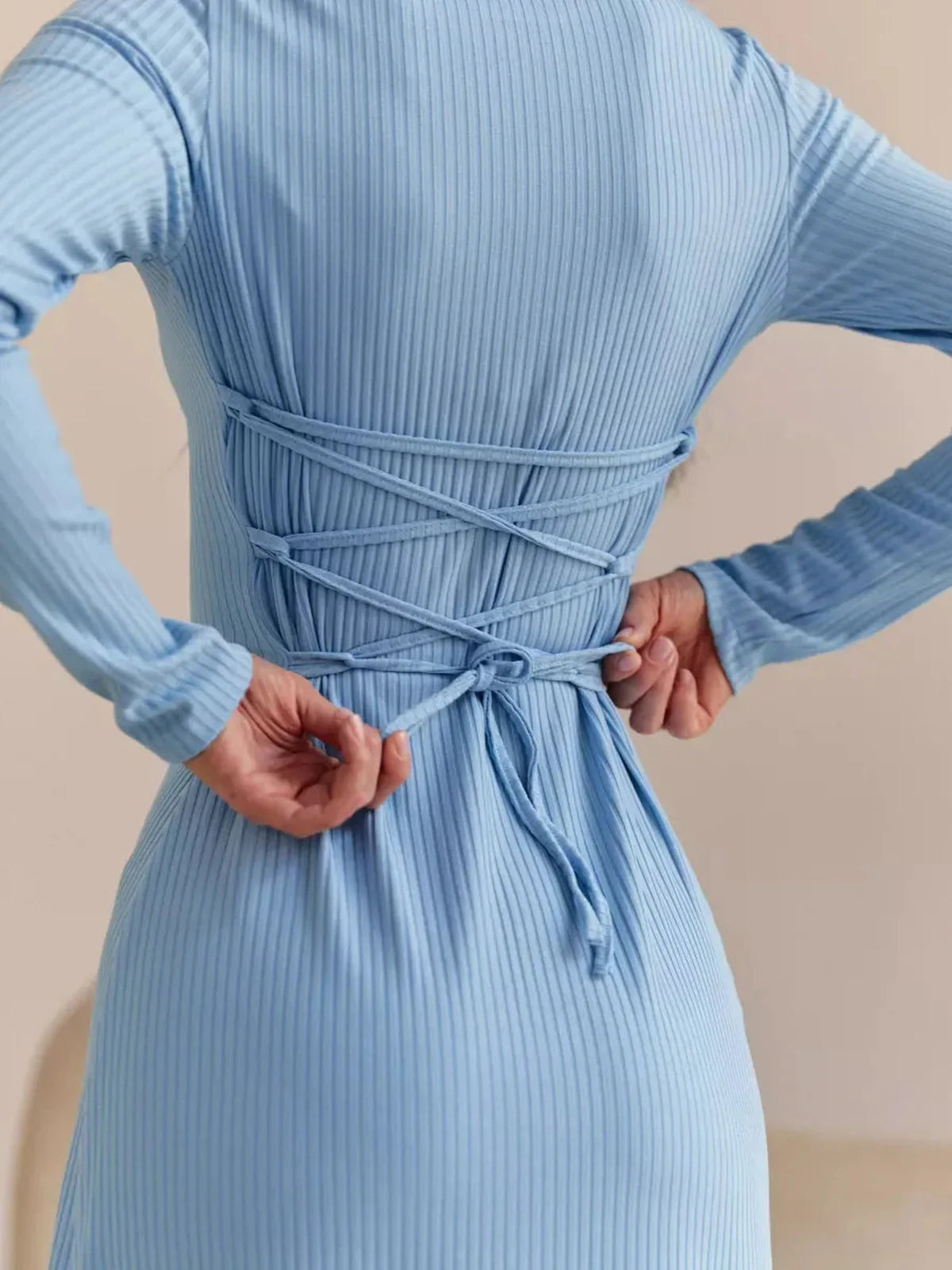 Close-up of the back of a blue midi dress featuring corset-style ties and a ribbed texture, highlighting elegant design.