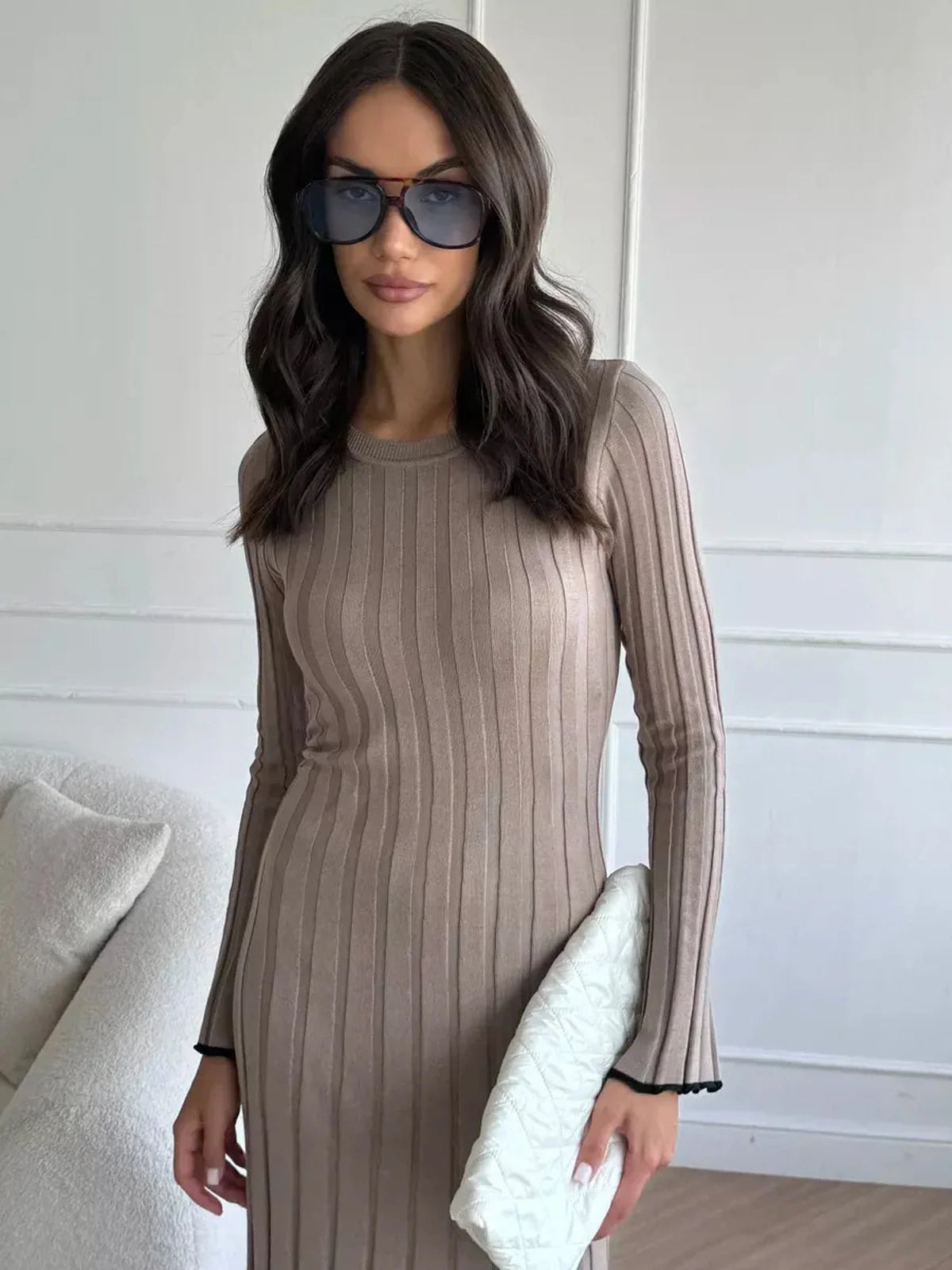 Elegant woman wearing a ribbed knit Contour Maxi Dress, styled with oversized sunglasses and a chic clutch.