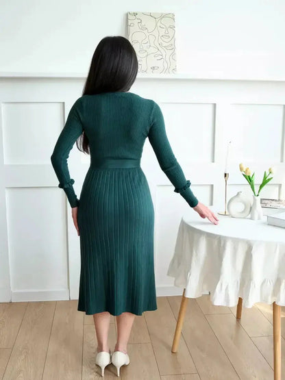 Back view of a woman in a ribbed knit emerald midi dress, showcasing pleated texture and elegant silhouette.