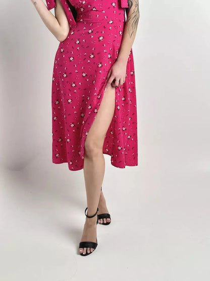 Model showcasing the Rosé Charm Midi Dress with floral print, featuring a thigh-high slit and chic black heels.
