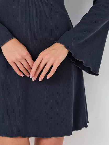 Close-up of hands on the Graphite Grace mini dress, highlighting its ribbed texture and flared sleeves.