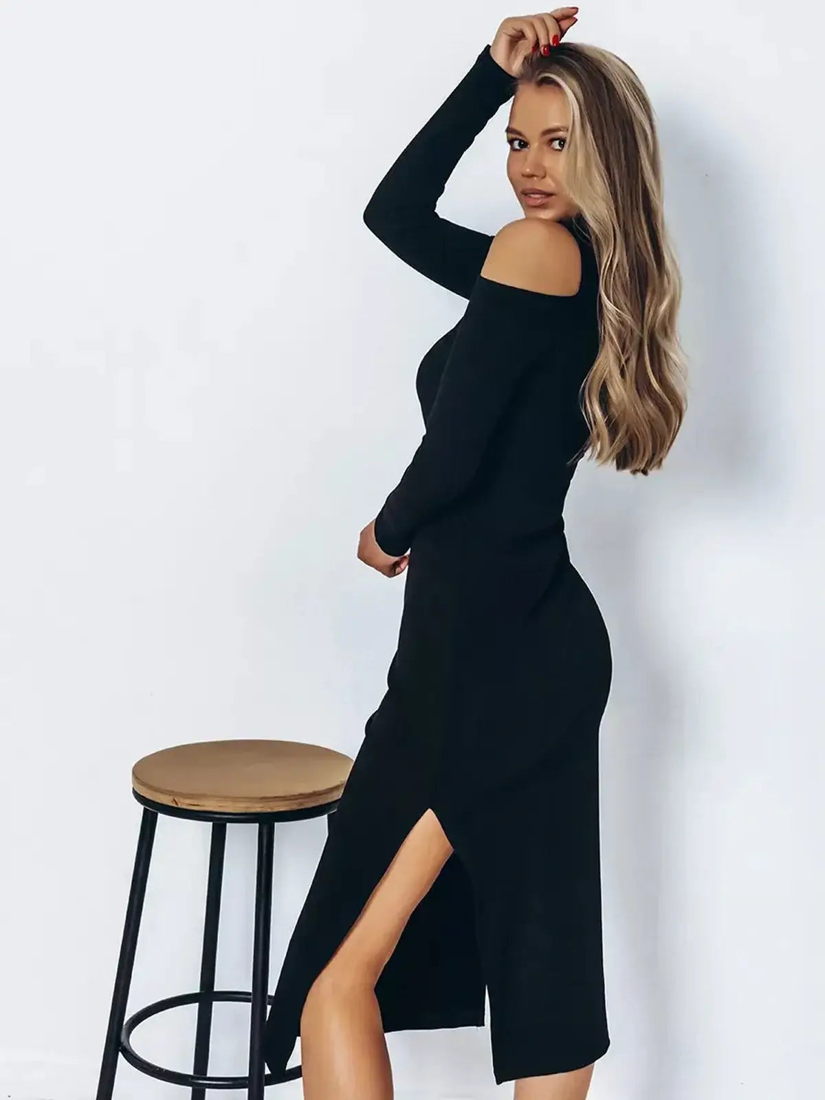 Woman in a black Shadow Midi Dress featuring elegant cutout shoulders and side slits, perfect for formal occasions.
