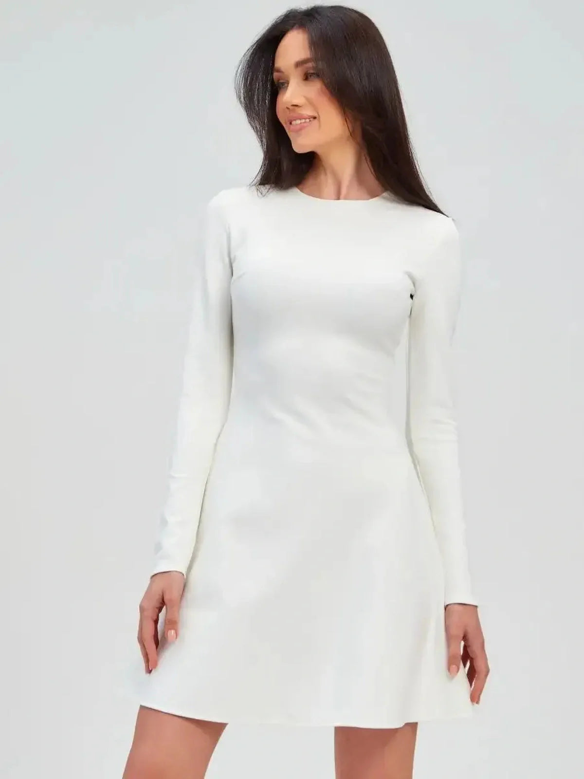 Model showcasing the Ivory Sculpt Dress, a minimalist white A-line mini dress with long sleeves.