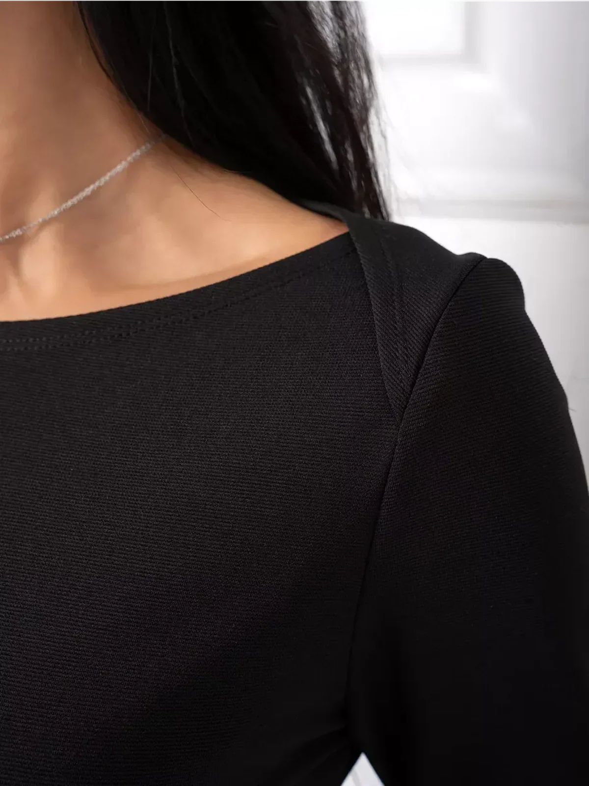 Close-up of the soft boat neckline of the Midnight Flow black mini dress, showcasing minimalist elegance perfect for various occasions.