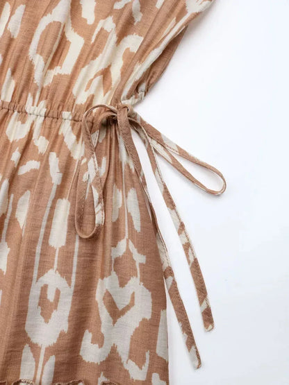 Close-up of the waist tie detail on the Nomad Tiered Midi Dress, featuring a light brown and cream geometric print.