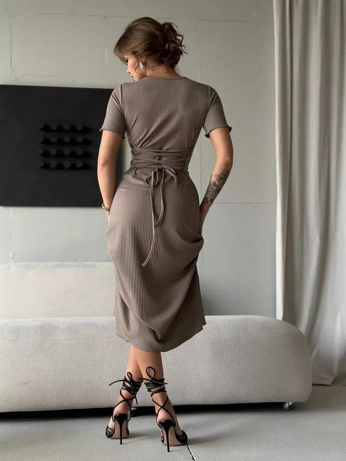 Stylish woman in a ribbed contour midi dress with lace-up back and heels, showcasing elegant fit and sophisticated style.