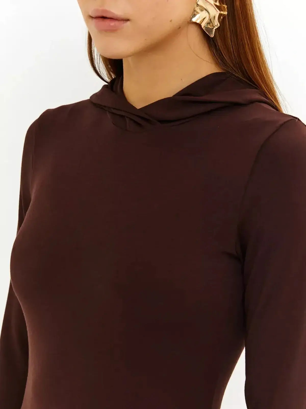 Close-up of a woman in a rich chocolate hooded maxi dress, showcasing elegance and modern style.