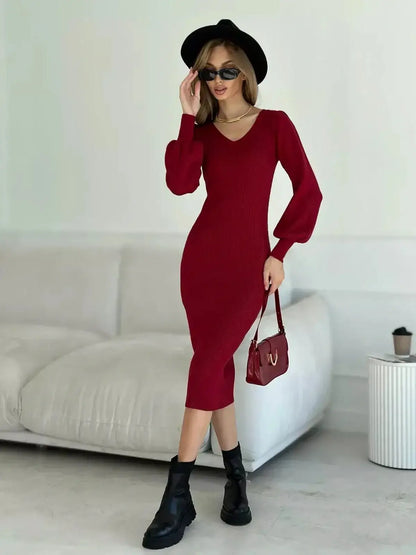 Model wearing a red ribbed knit midi dress with V-neckline and long sleeves, styled with a black hat and boots.