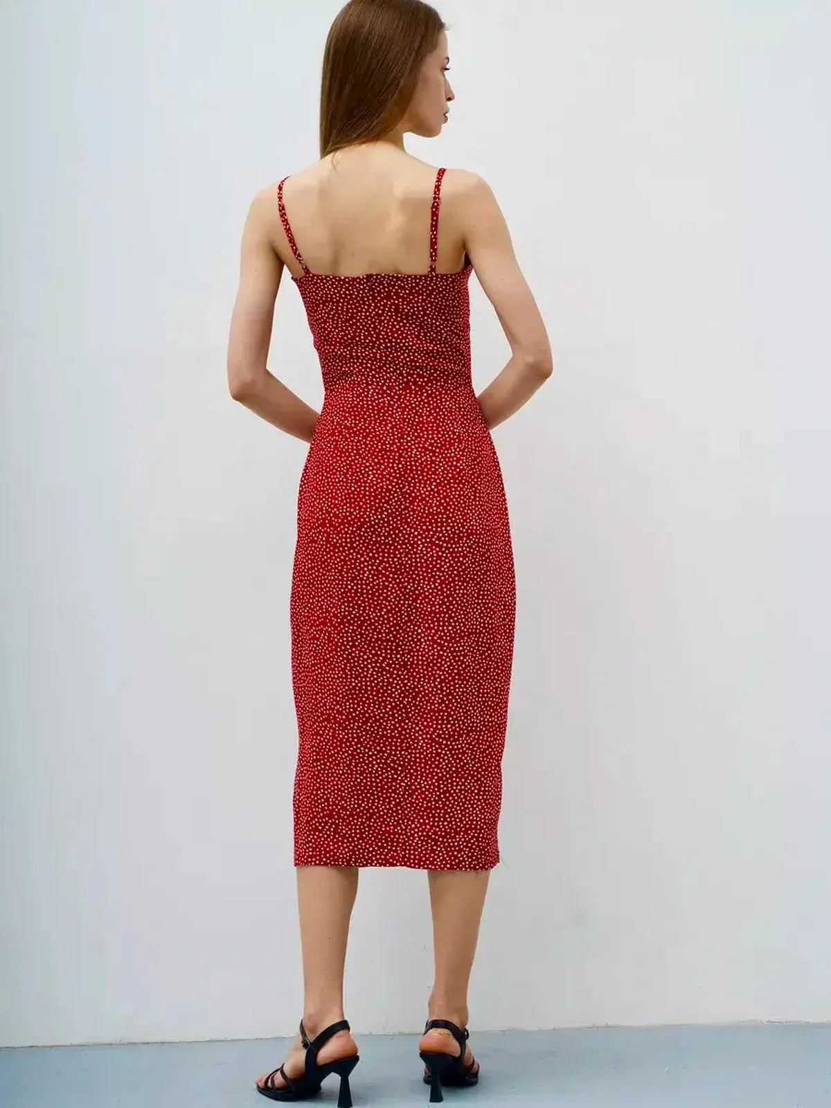 Back view of a woman in a Cherry Dots Midi Dress with a fitted style and playful red polka dot pattern.