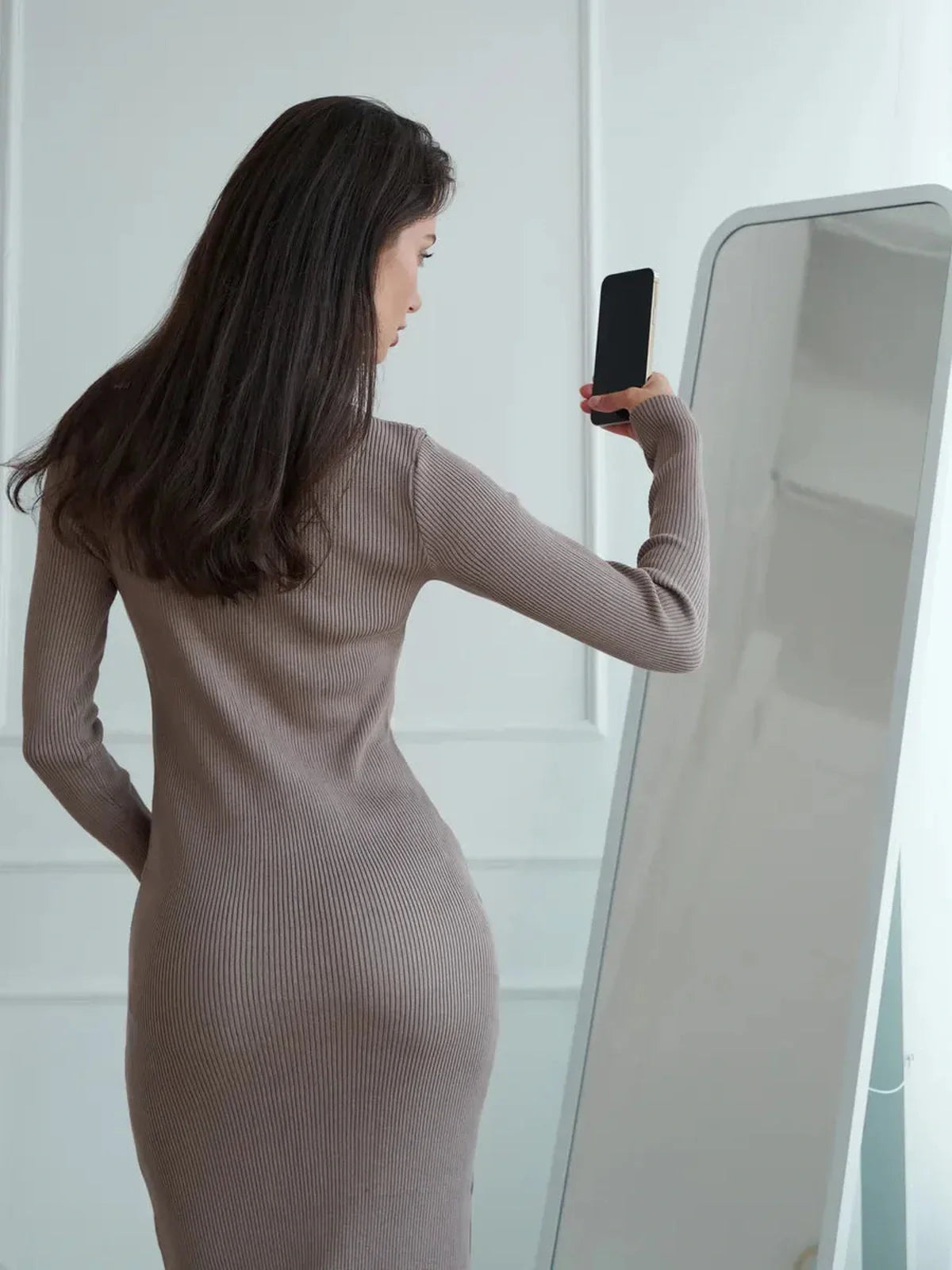 Model in a ribbed knit contour midi dress, showcasing its flattering silhouette and elegant design in a soft cappuccino tone.