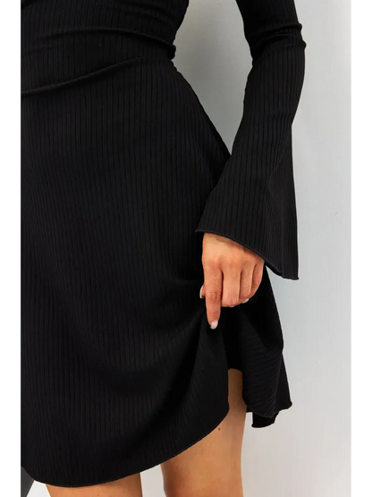 Close-up of a woman wearing a black ribbed Flare Charm Mini Dress with fluted sleeves and a playful silhouette.
