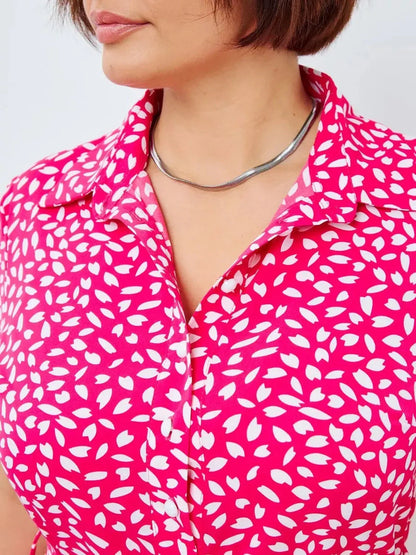 Close-up of a woman wearing a pink Petal Pop Midi Dress with abstract white petal print and a stylish necklace.