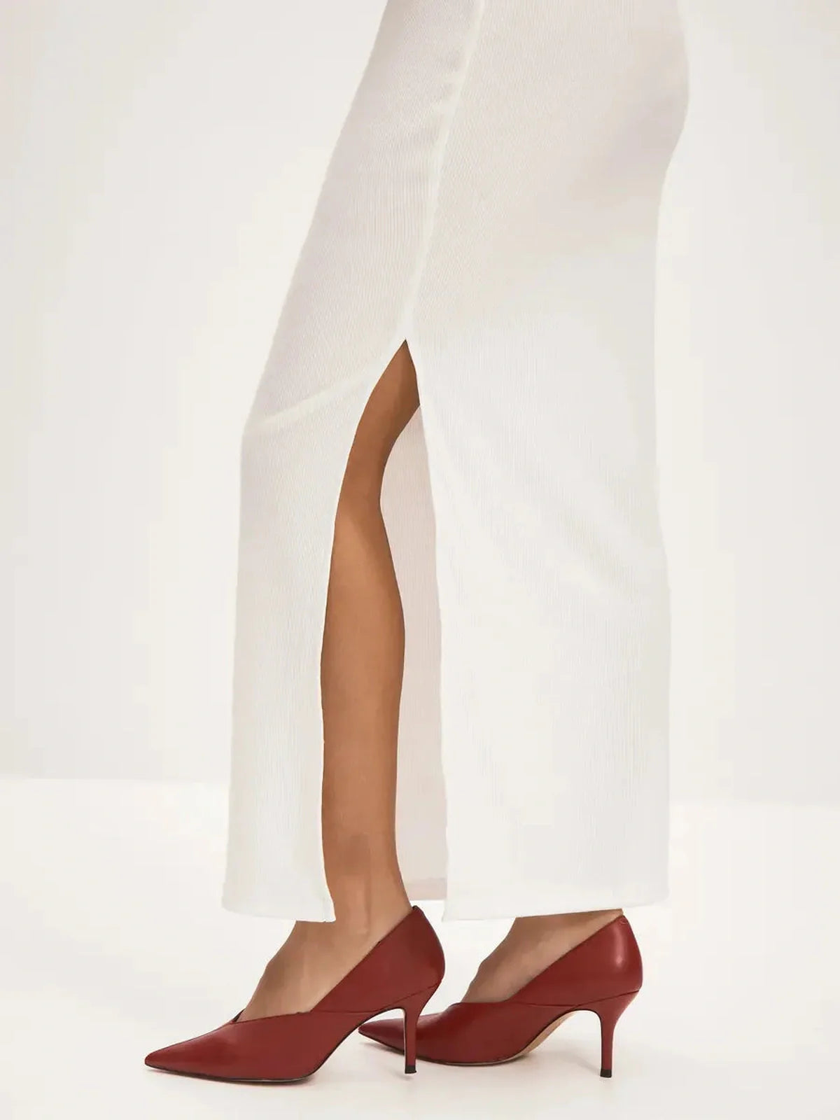 Close-up of a white maxi dress with a side slit and red high heels, showcasing elegance for summer and formal occasions.