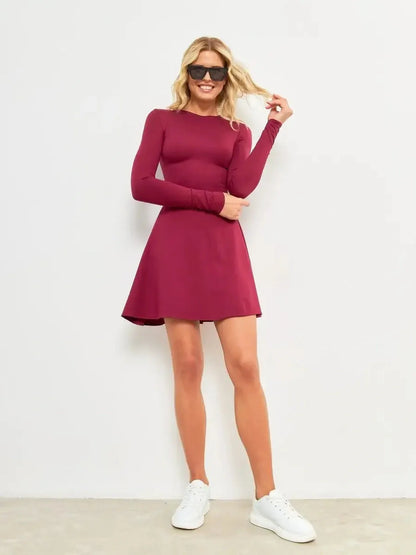 Model wearing a burgundy Wine Flare Mini dress with long sleeves, styled casually with white sneakers.