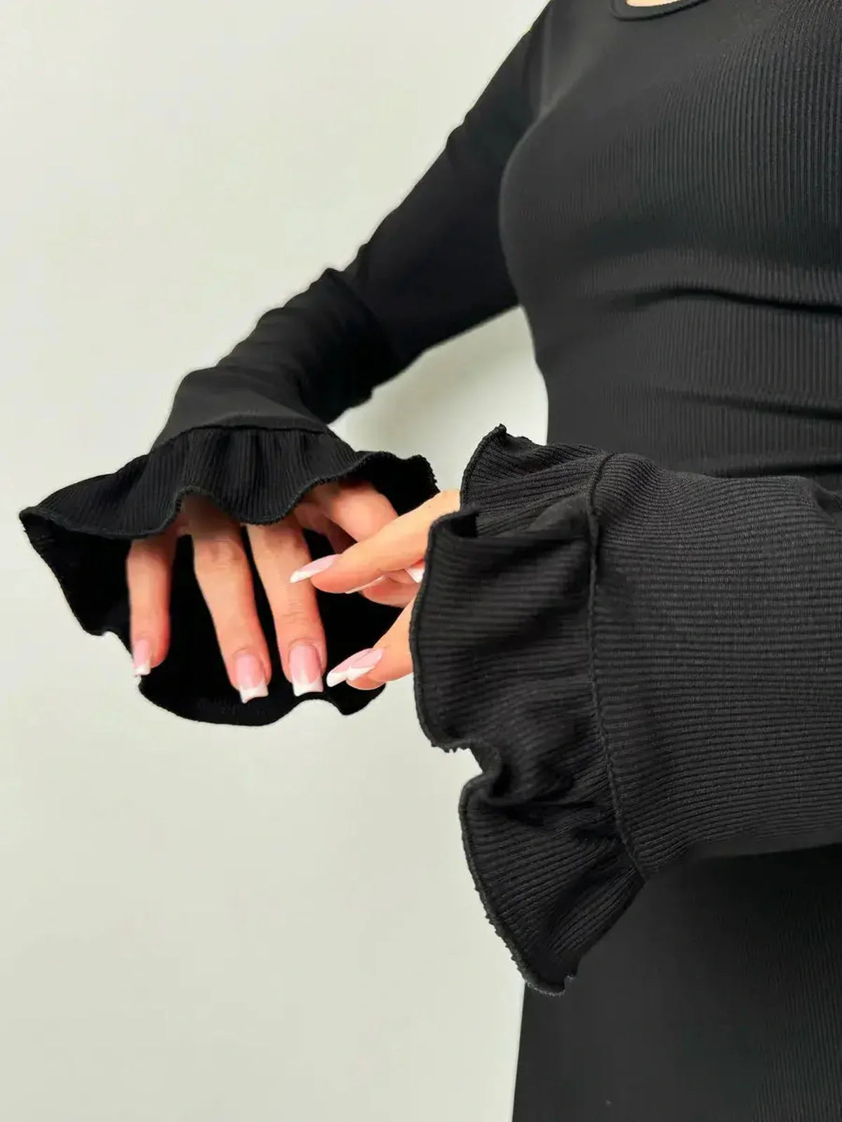 Close-up of ruffled sleeves on a black velvet lace mini dress, showcasing chic design for formal occasions.