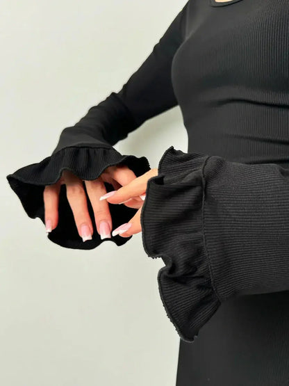 Close-up of ruffled sleeves on a black velvet lace mini dress, showcasing chic design for formal occasions.