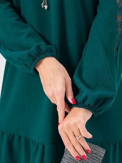 Close-up of a green lace mini dress featuring gathered sleeves and a model's hand holding a stylish clutch.