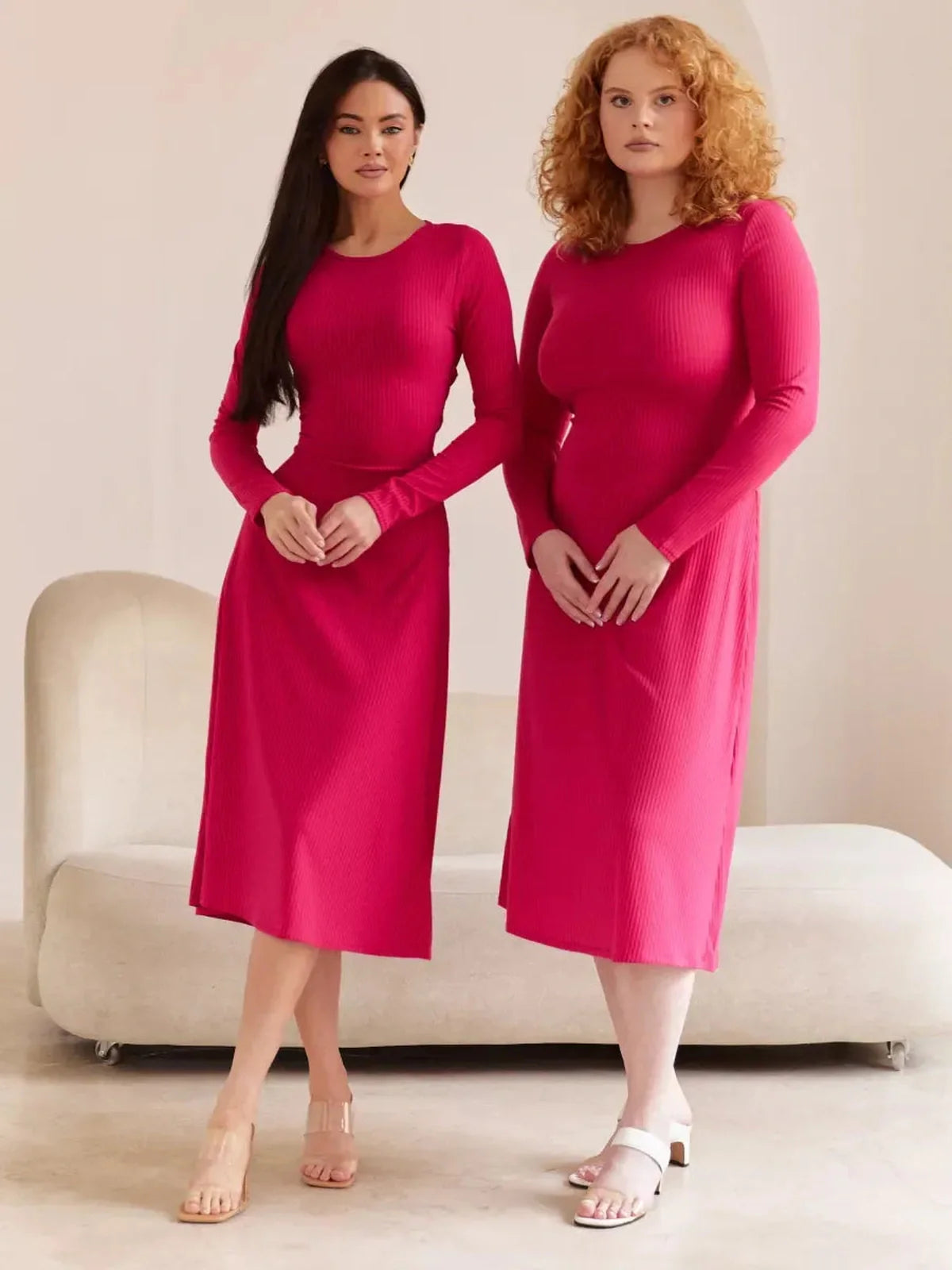 Two models showcasing the Contour Midi Dress in vibrant pink, featuring a ribbed knit design and elegant silhouette.
