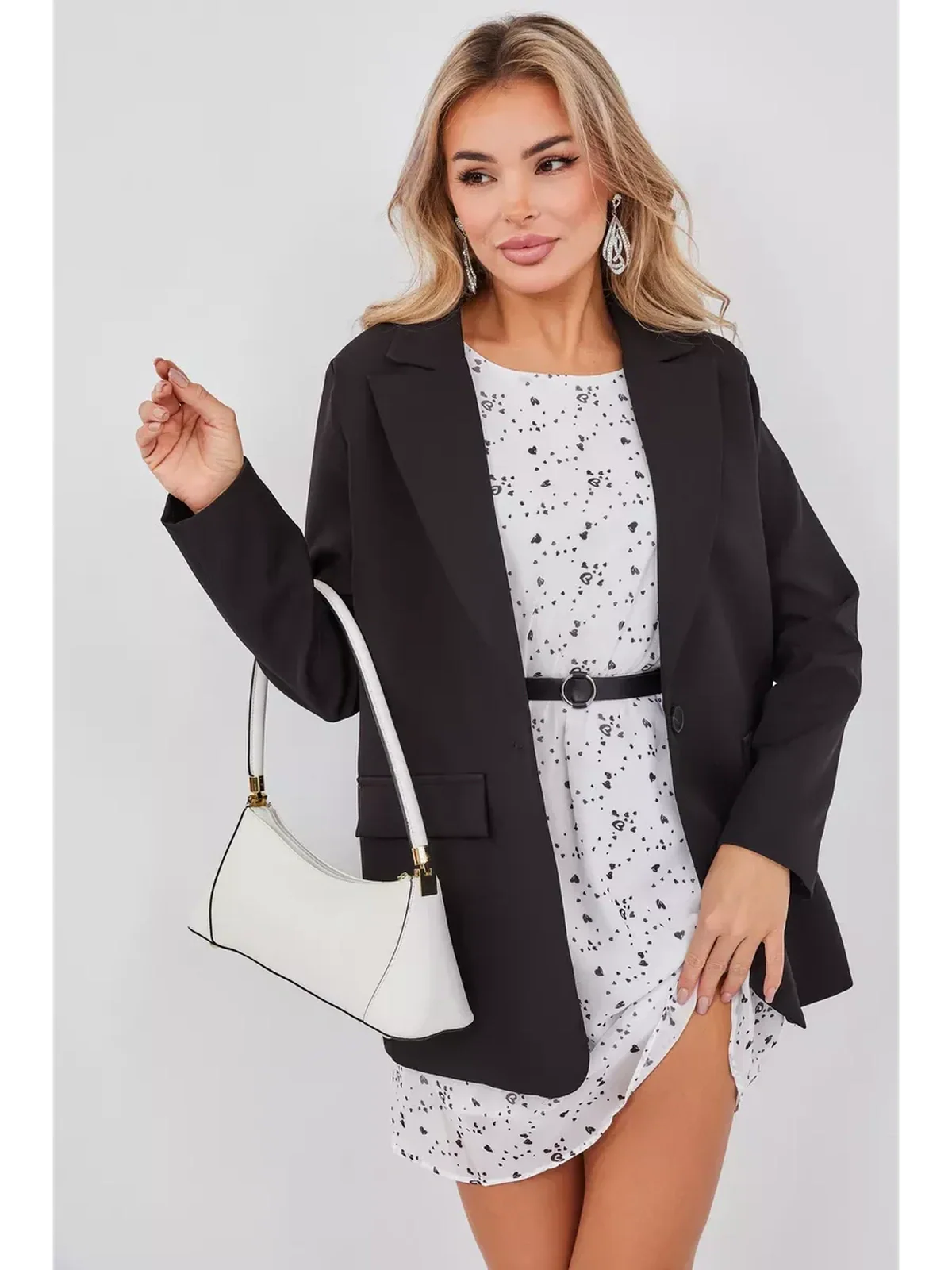 Stylish woman wearing Monochrome Muse Mini Dress with a black blazer, holding a white handbag for a chic look.