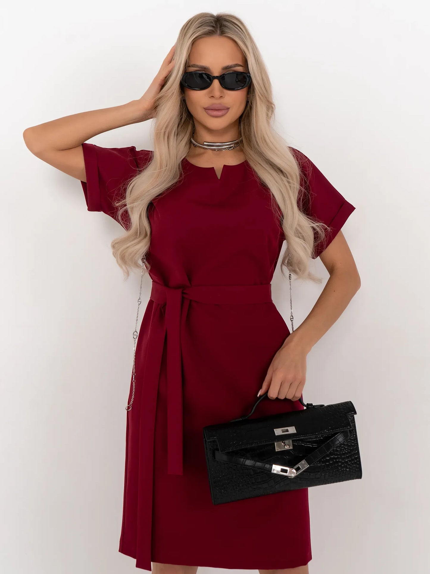 Model showcasing the Crimson Code mini dress, a wine-red, structured piece with a sleek silhouette and detachable belt.