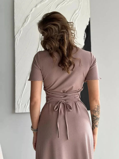 Back view of a woman in a ribbed contour midi dress with lace-up waist, showcasing its elegant fit and soft texture.