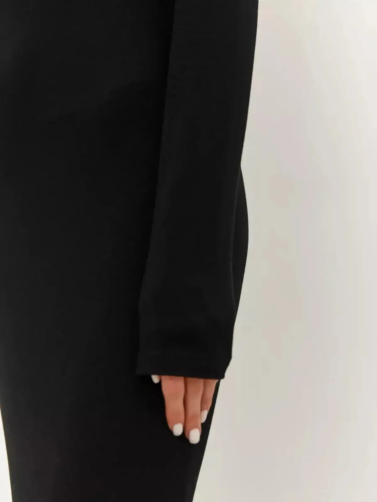 Close-up of a woman's hand on the sleeve of a fitted black maxi dress, showcasing its minimalist elegance.