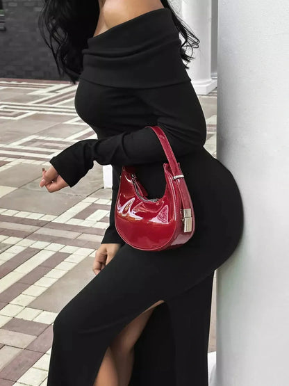 Elegant black maxi dress with off-shoulder neckline and side slit, paired with a stylish red handbag.