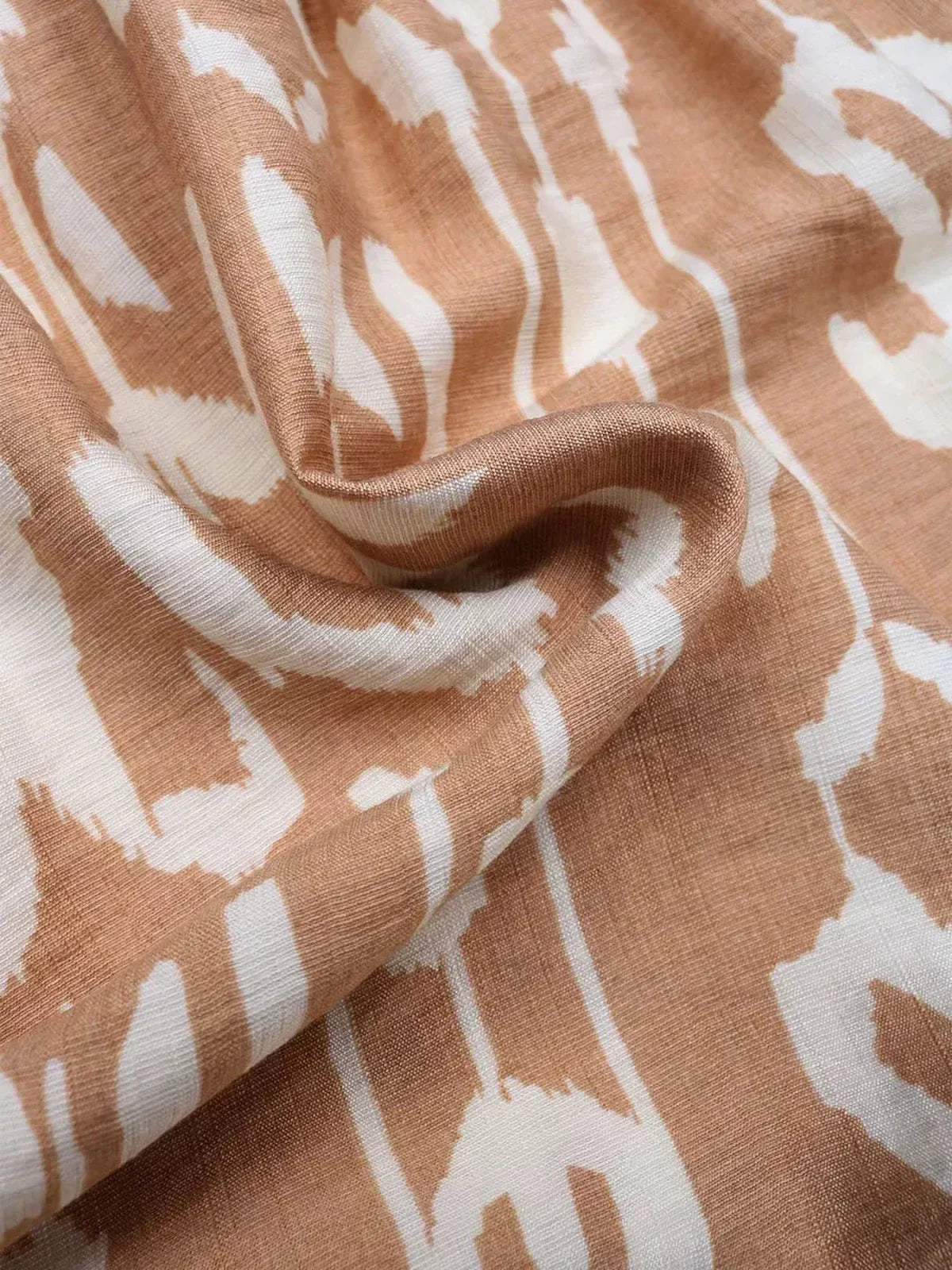 Close-up of lightweight fabric with a bohemian geometric print in soft brown and cream tones, ideal for dresses.