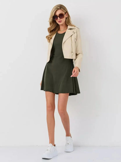 Chic woman in an olive green mini dress paired with a beige jacket and sneakers, perfect for casual outings.