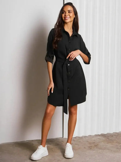Model showcases the Urban Edit Mini black shirt dress with a cinched waist and button-down design, ideal for versatile styling.