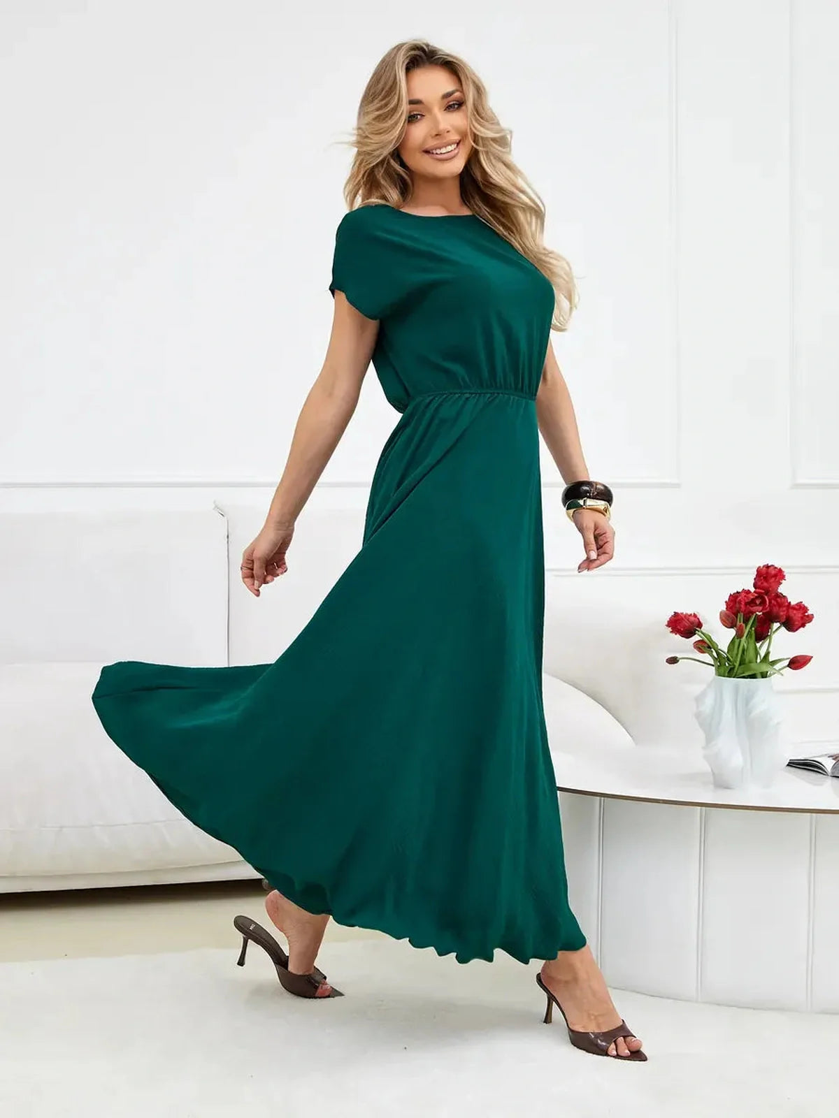 Model wearing an elegant emerald green maxi dress with a cinched waist and flowing silhouette, perfect for summer or special occasions.