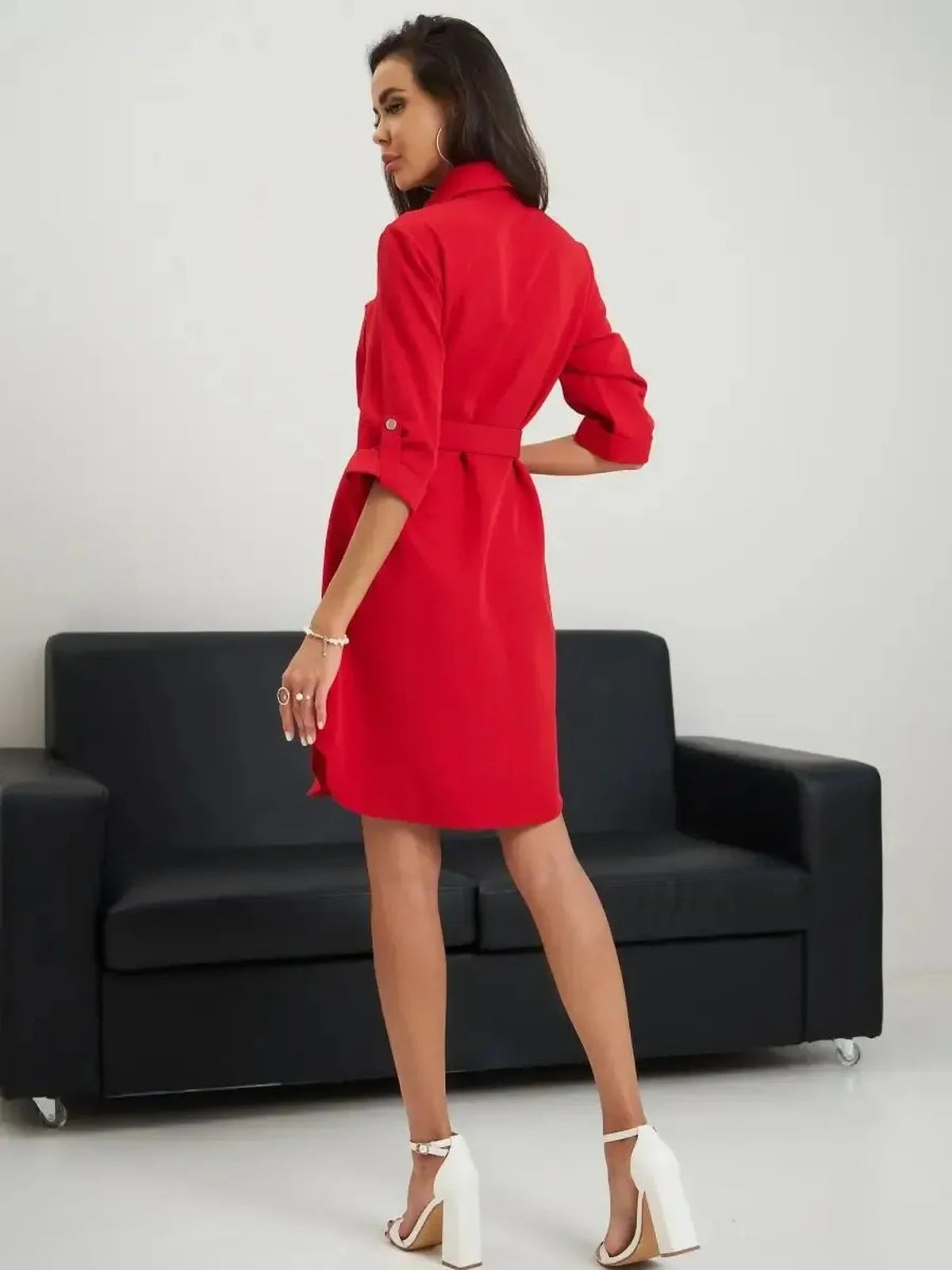 Back view of a woman in a vibrant red mini dress, showcasing its sleek silhouette and cinched waist design.