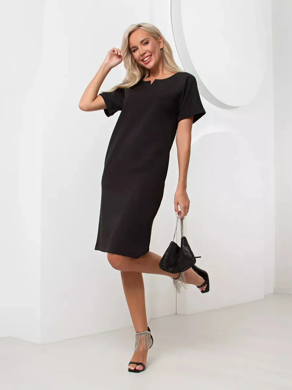 Stylish woman modeling the Modern Grace black mini dress with cuffed sleeves and self-tie belt.