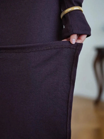 Close-up of a hand holding the pocket of the Elegance Maxi Dress, showcasing its stylish ribbed texture and refined details.