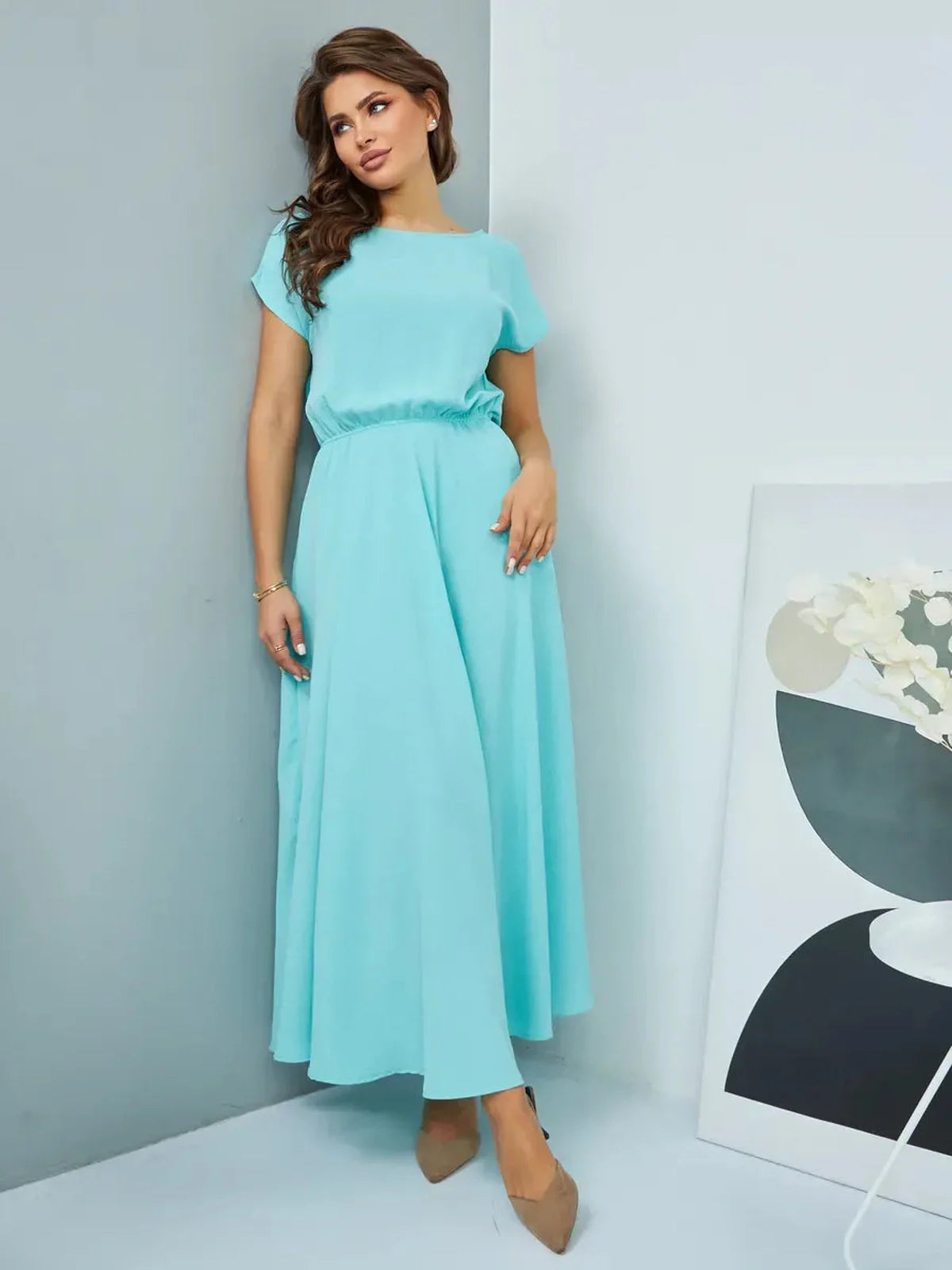 A woman wearing a light blue maxi dress with short sleeves and a cinched waist, styled elegantly for special occasions.