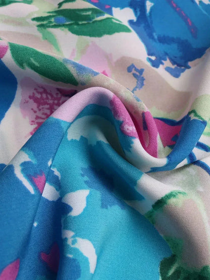 Close-up of vibrant watercolor floral fabric showcasing pink, teal, and green hues for a midi dress.