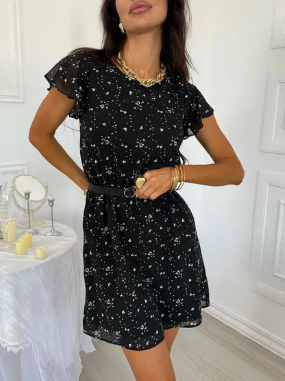 Chic black chiffon mini dress with flutter sleeves, a cinched waist belt, and playful all-over print, perfect for summer events.