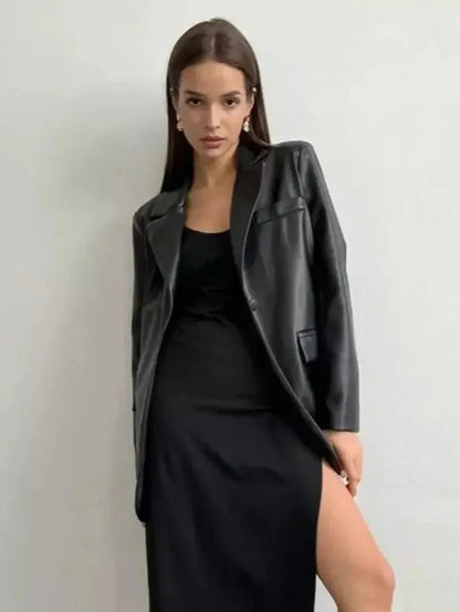 Fashionable woman in a black leather jacket over a sleek black midi dress with a side slit.