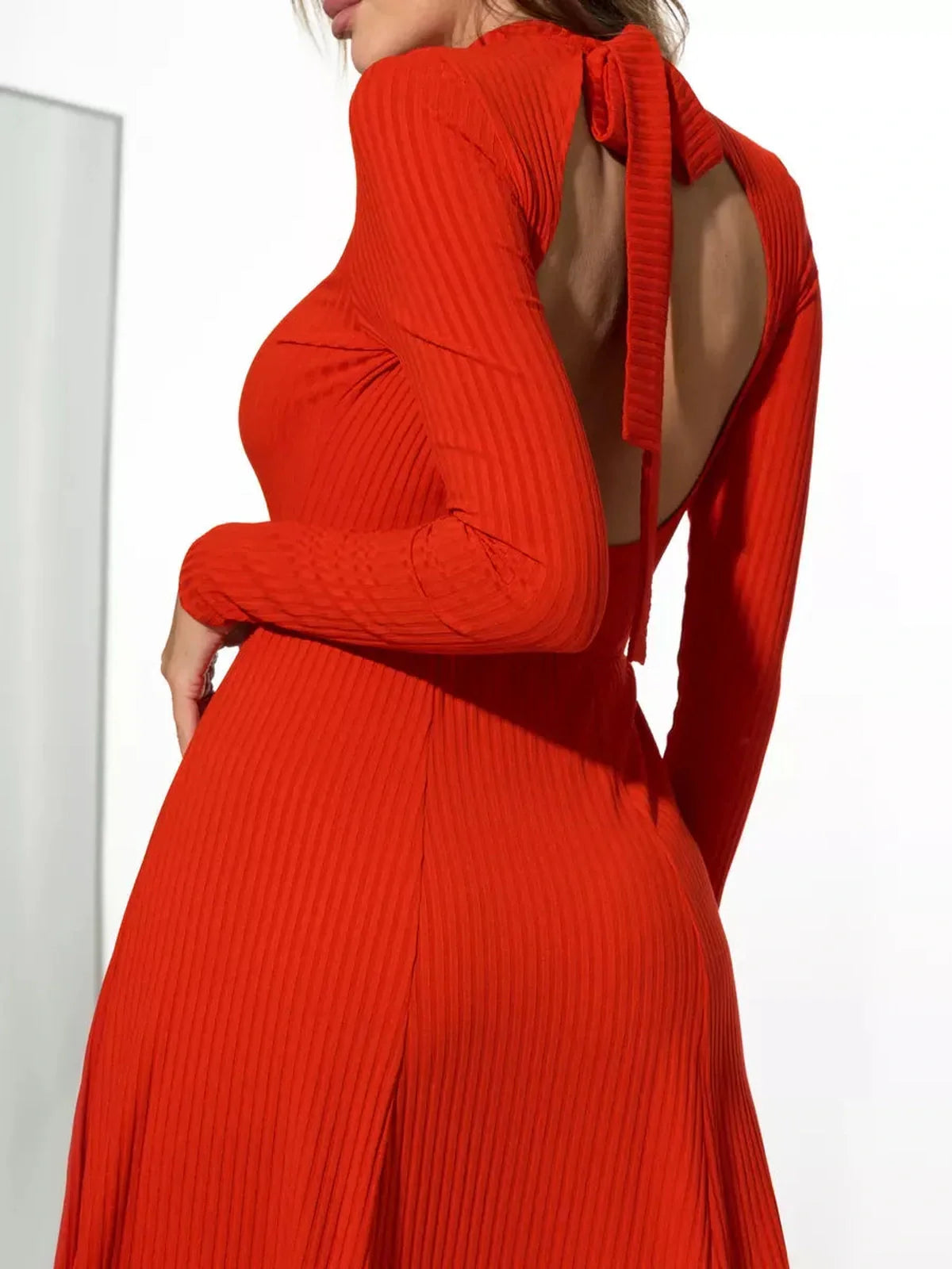 Backless crimson midi dress with long sleeves and stylish tie detail, perfect for weddings and upscale events.