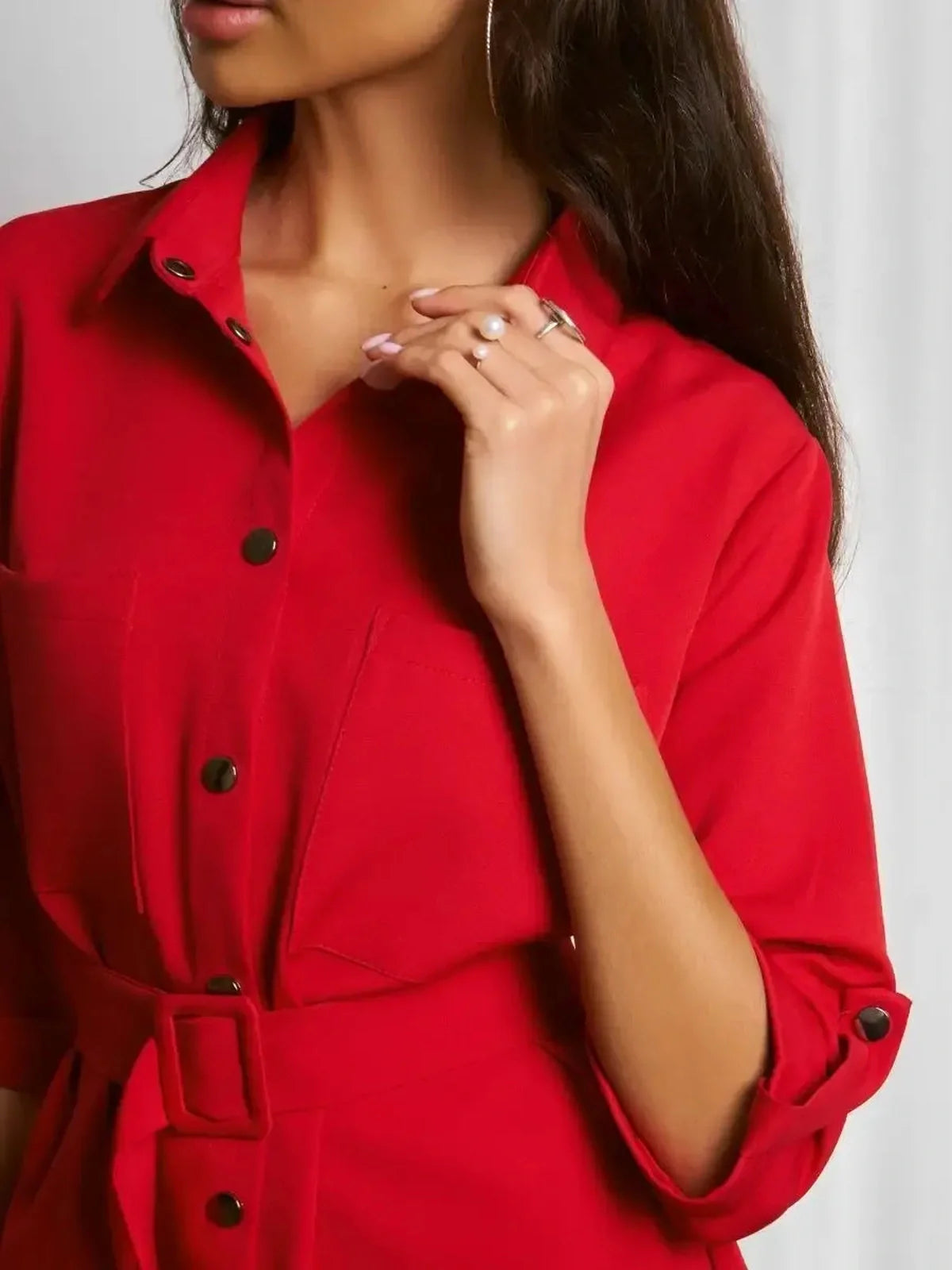 Close-up of a woman wearing a scarlet belted mini dress with button details and a tailored silhouette.