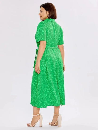 Back view of a woman in a green Garden Dot Midi Dress, featuring a tie waist and dotted pattern, perfect for summer occasions.