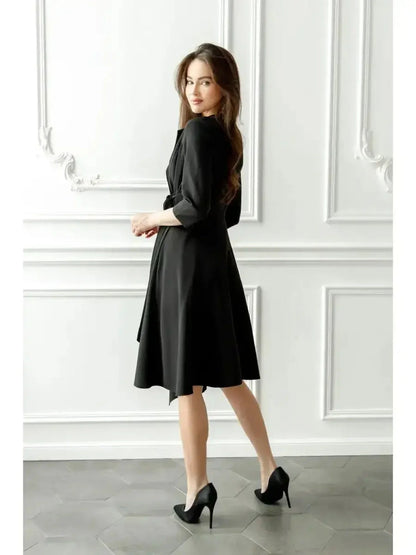 Elegant woman in a black midi dress, showcasing a wrap silhouette and flowing hem, suitable for formal events.